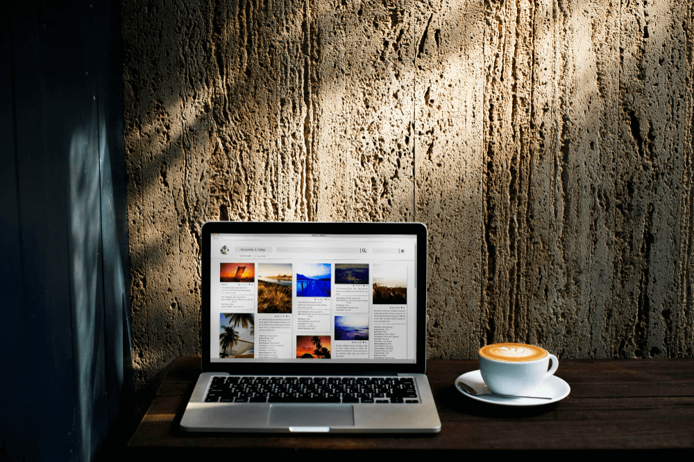 a laptop with a web page opened and a cup of coffee